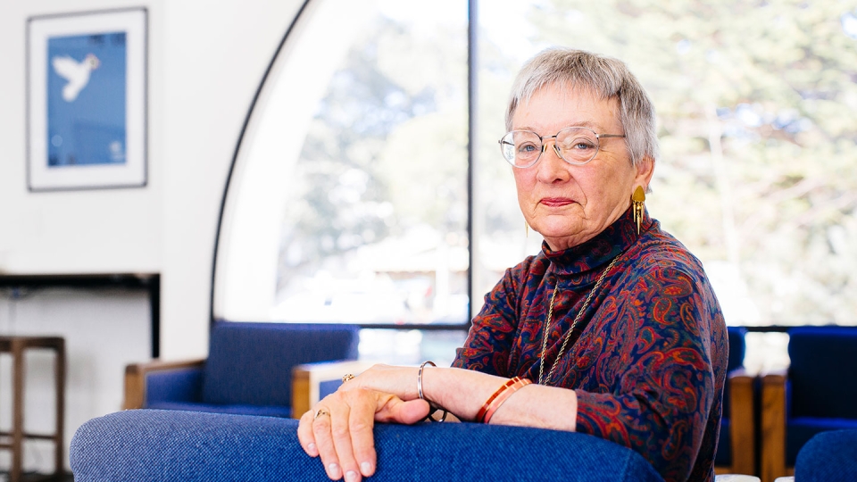 A Middlebury Institute alum sits in an office on campus looking at the camera.