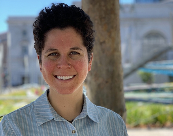 Headshot of speaker Clesi Bennett, smiling, outside by a tree in a city landscape