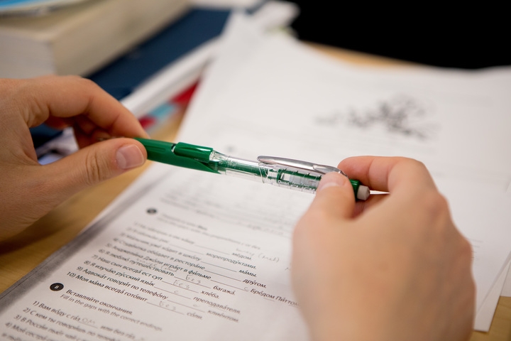 Person holds pen over a piece of paper
