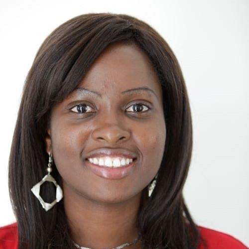 Dr. Jola Ajibade, bright eyes, bright smile with brown shoulder length hair in stylish cut, with large stylish earings and a red blouse