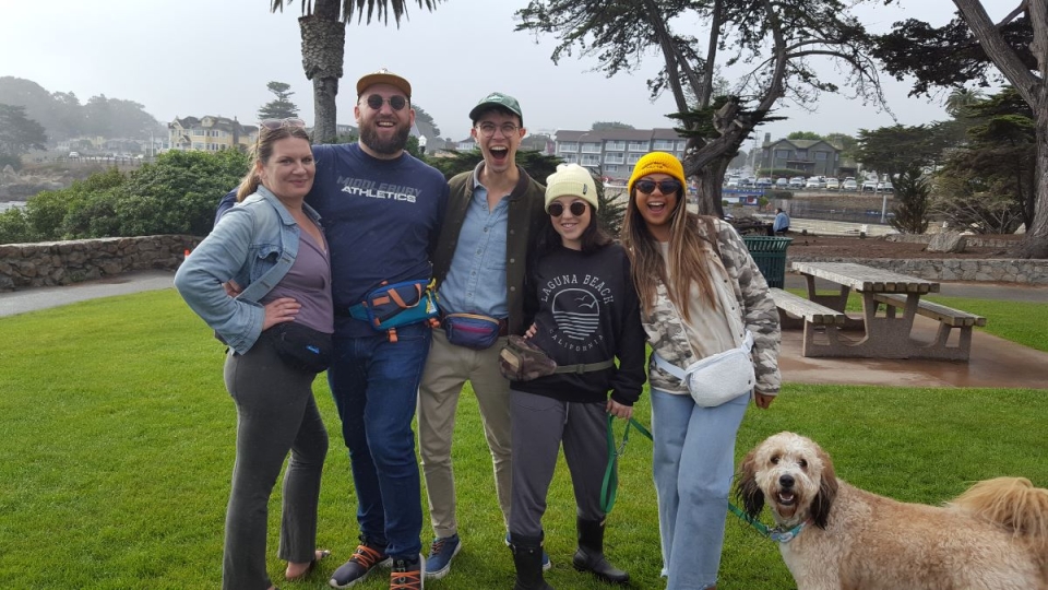 a group of people, and one cute dog, showing off fanny packs