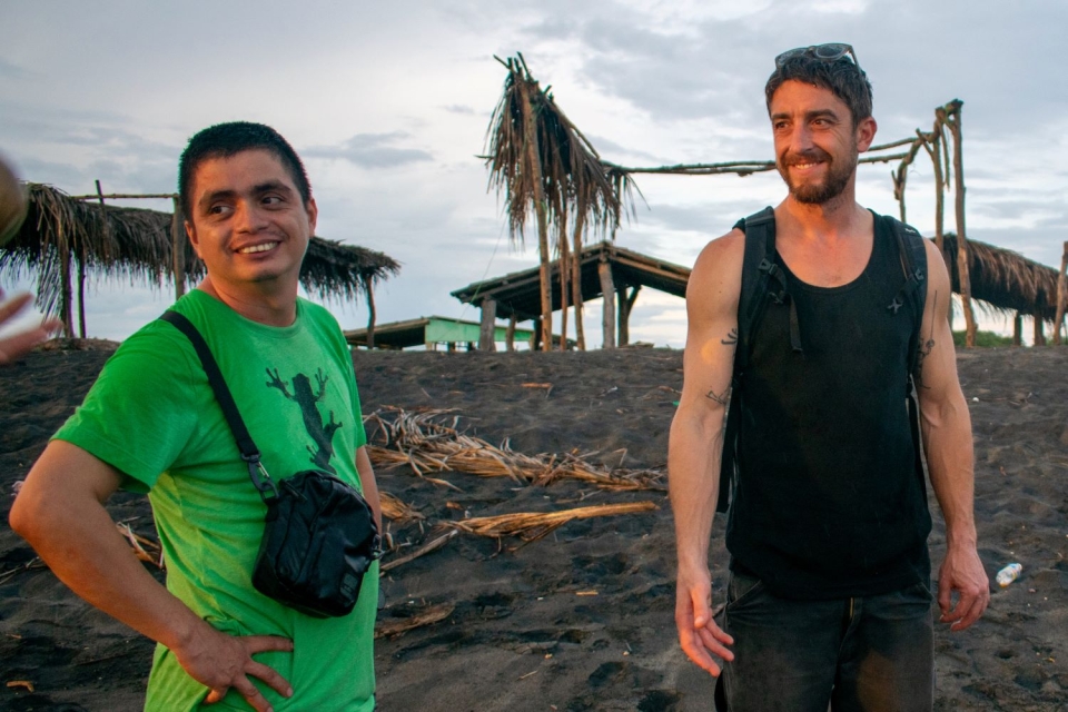 Jose María Argueta and Nick Rahaim looking toward the setting sun on a black sand beach