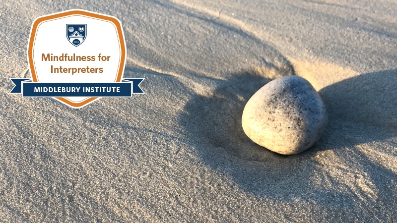 Rock in the sand with the Mindfulness for Interpreters digital badge overlayed