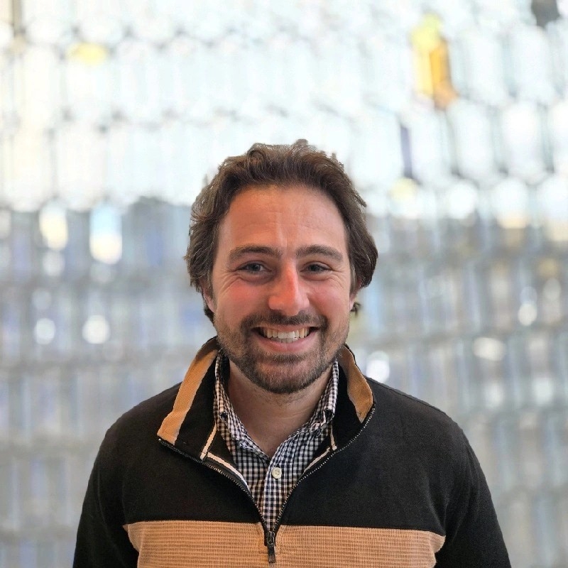 Alex Shahbazi smiling brightly in a yellow and black jacket