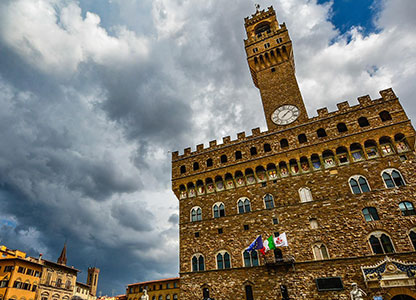Top of a cathedral in Florence, Italy with clouds and sky in the background.