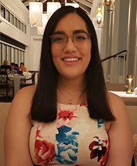 Megan Spitzer smiling brightly, eyes bright, long dark hair in a grand hall or building