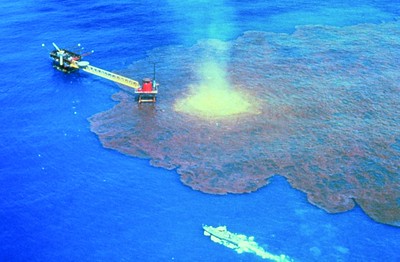 Blue water with sickening pink oil slick and yellow/orange fire on the ocean.  The blownout offshore oil well ran wild for 9 months and spilled over 140 million gallons of oil into the Bay of Campeche in the Gulf of Mexico,1979.