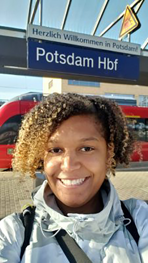 Kimberly Aiken, smiling taking selfie in front of red train taking her to Norway