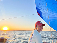 Maya Hoffman on the deck of a sailboat at sunrise, smiling, in her element
