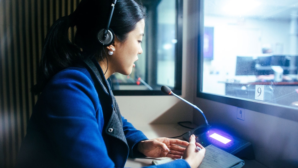 A young female student speaking into a mic in a broadcast studio.