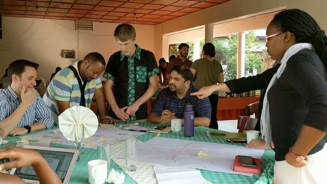Team of DPMI participants around a table discussing a project