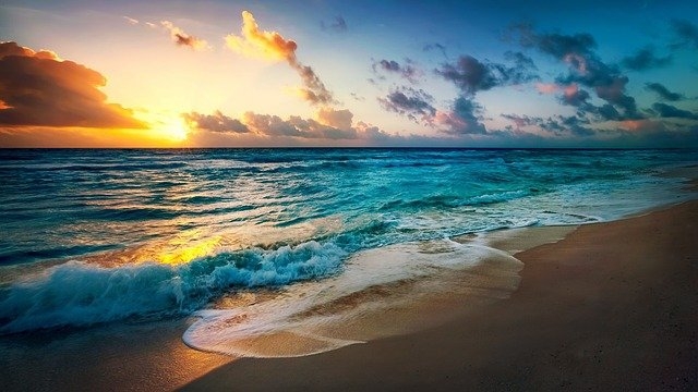 Orange sunset over turquoise blue water at a broad sandy beach