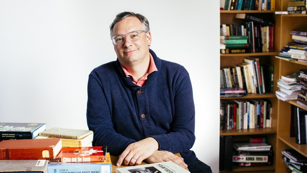 Dr. Jeffrey Lewis sitting at a desk with a pile of books