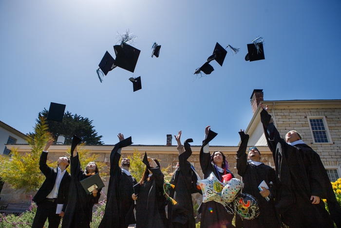 Group of spring 2022 graduates throw their caps into the air