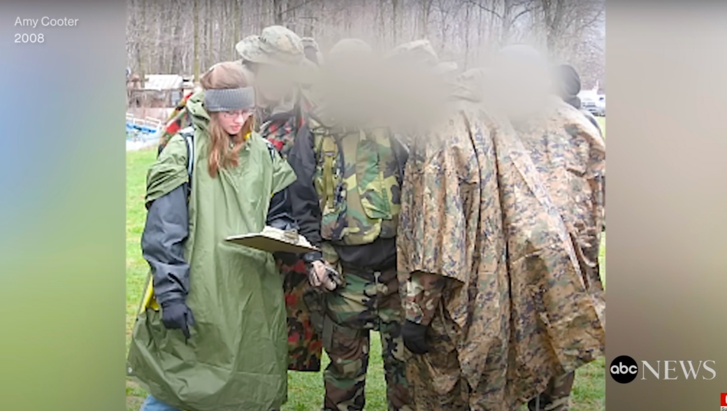Photo of a woman showing a clipboard to a group wearing camouflage outdoors.