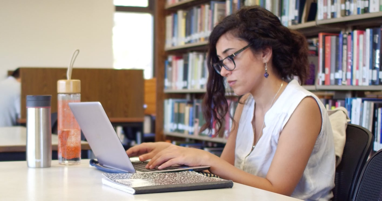 A female student works on her laptop computer in the library.