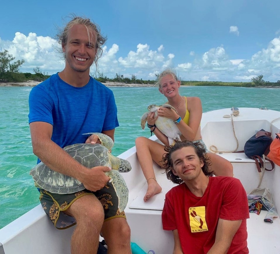 Sean McClellan in Bahamas with Middlebury Social Impact Corps, he is seen sitting on boat, holding sea turtle
