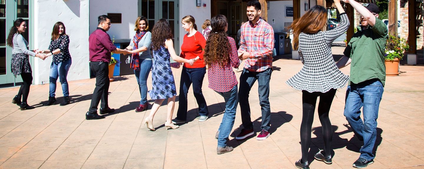 Students participate in an outdoor square dance on the campus patio.