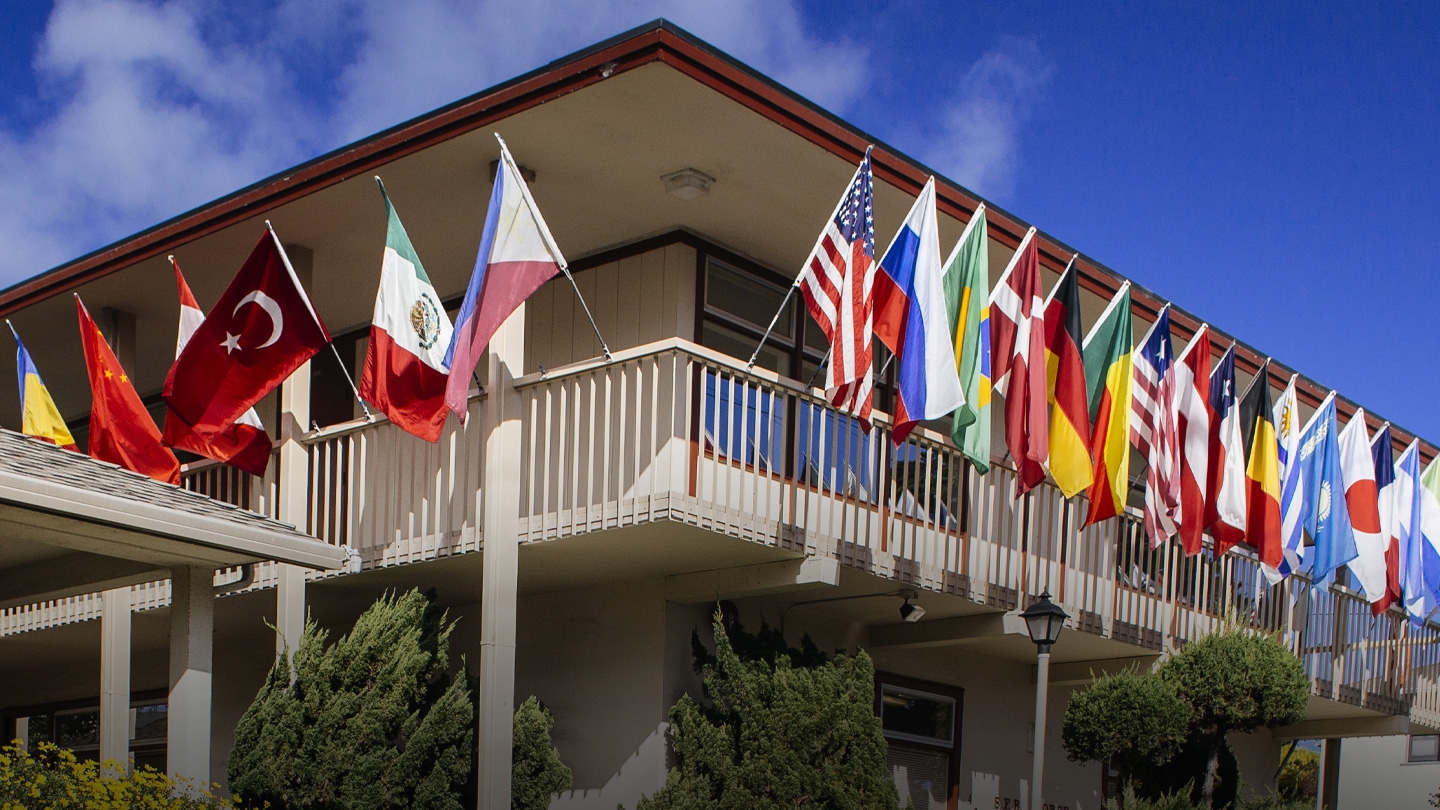Flags of several countries on either side of the corner of a building on campus
