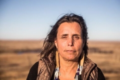 Winona LaDuke looking pensive with sunset lighting in an expansive outdoor space