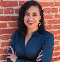 Profile image of a smiling Erica Williams standing in front of a red brick wall, arms folded
