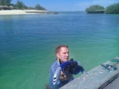 Bryce Bray holding snorkel gear while he wades in a large body of water