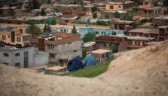 View of a neighborhood in Kabul from a hill. Two people site on the hill in the foreground.