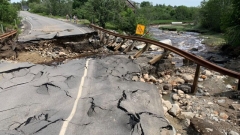 A broken up road and guardrail, flood damaged and warped