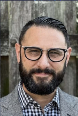 Photo of Vincent Intondi, man wearing black rimmed glasses, black beard and hair.