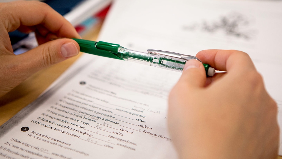 A student's green pen is poised over the Language Placement Test.