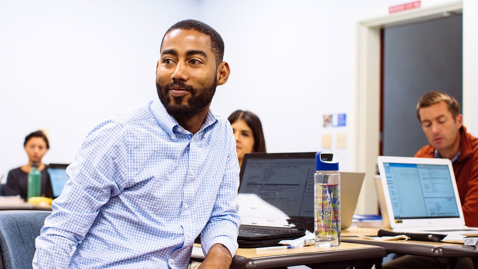 A student in a classroom turns to watch a presentation.