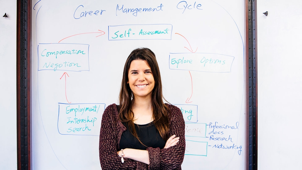 A female student stands in front of a whiteboard.