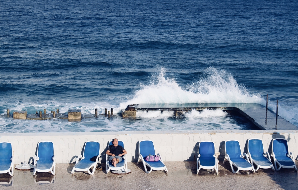 Man Relaxing in Lawn Chair with Waves Crashing Behind Ominously