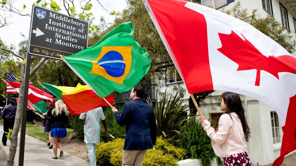Students walking through campus holding flags from various countries.