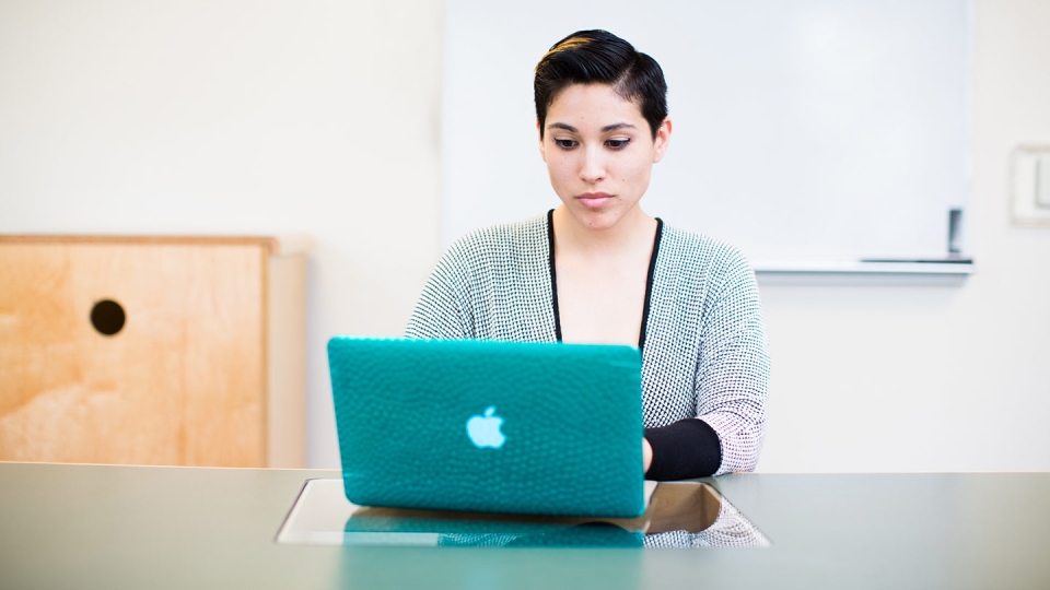 Woman sitting at table working on her computer.