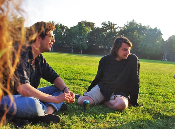 Two people sitting on grass in a park