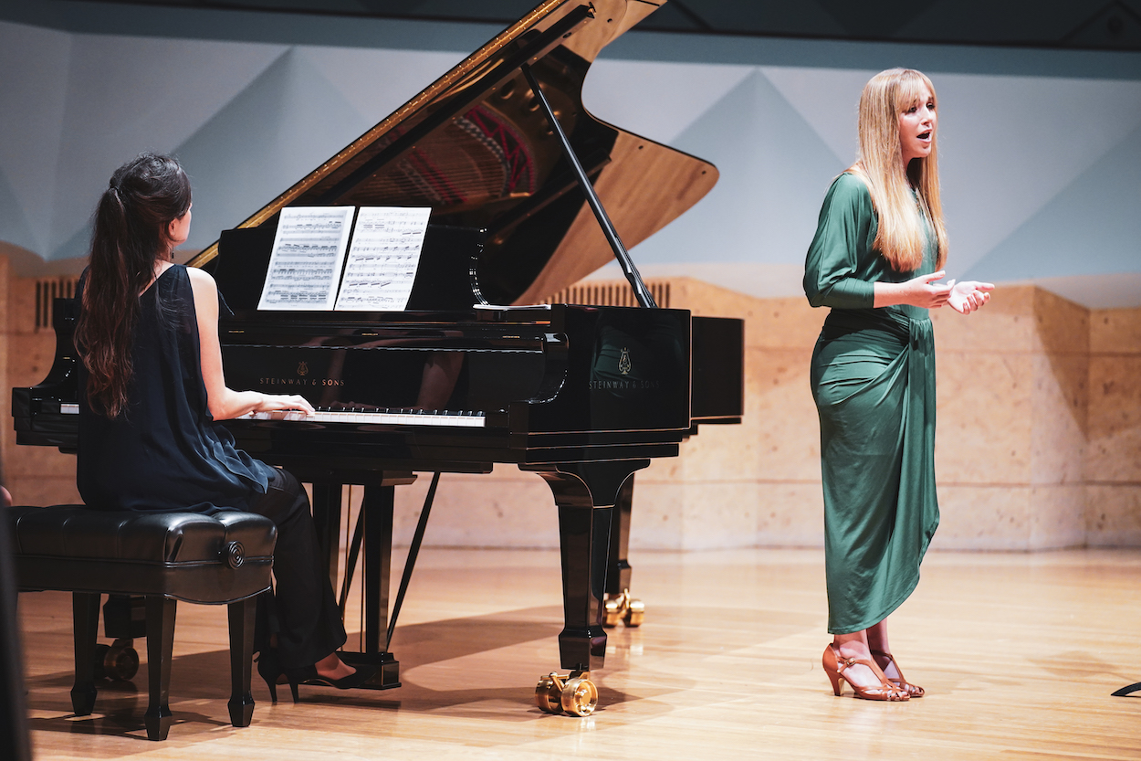 A singer and a pianist perform together on stage.