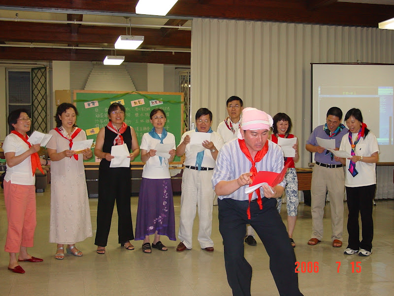 A man in a pink hat and red scarf reads his lines in a performance. 