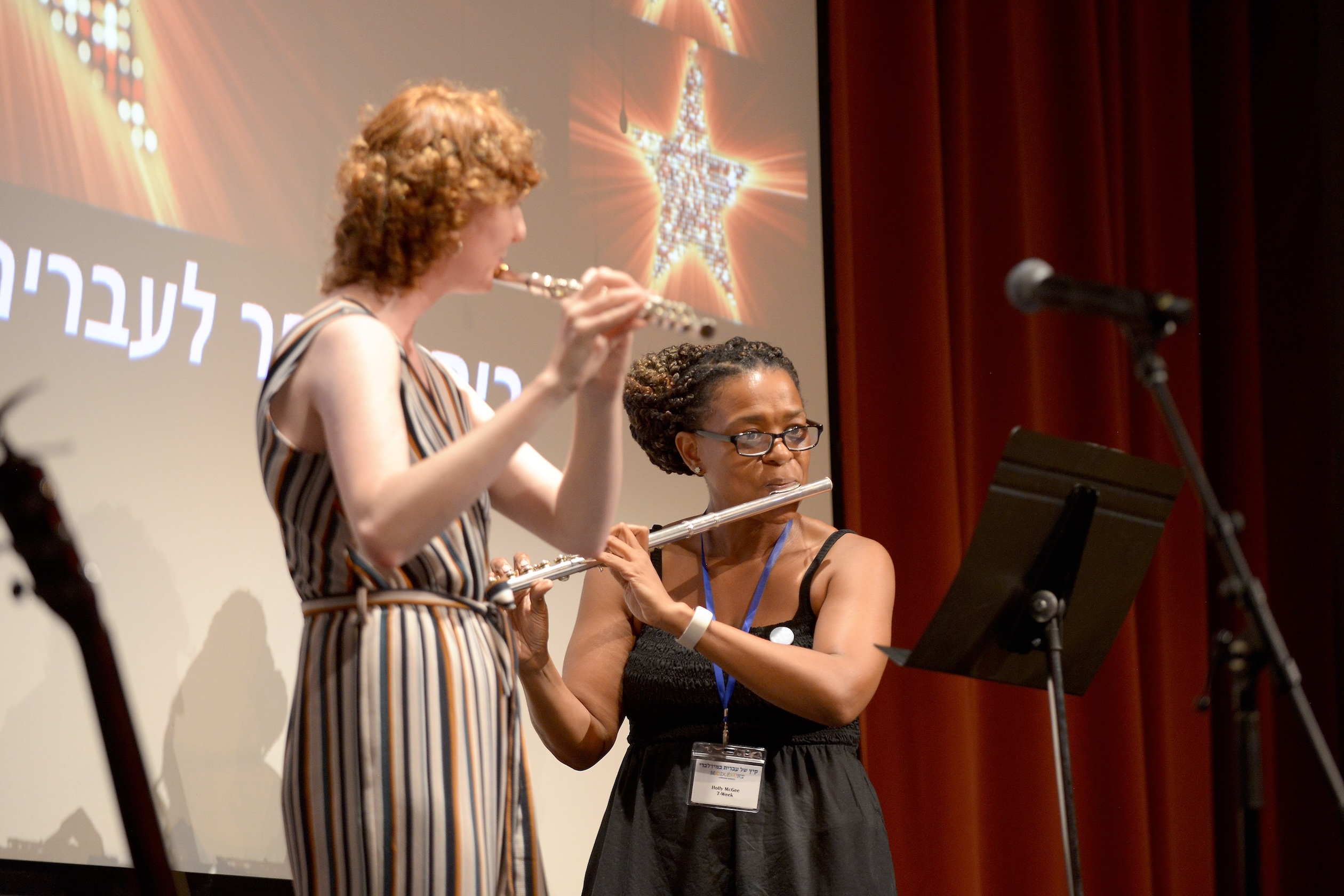 Two students play the flute together on stage. 