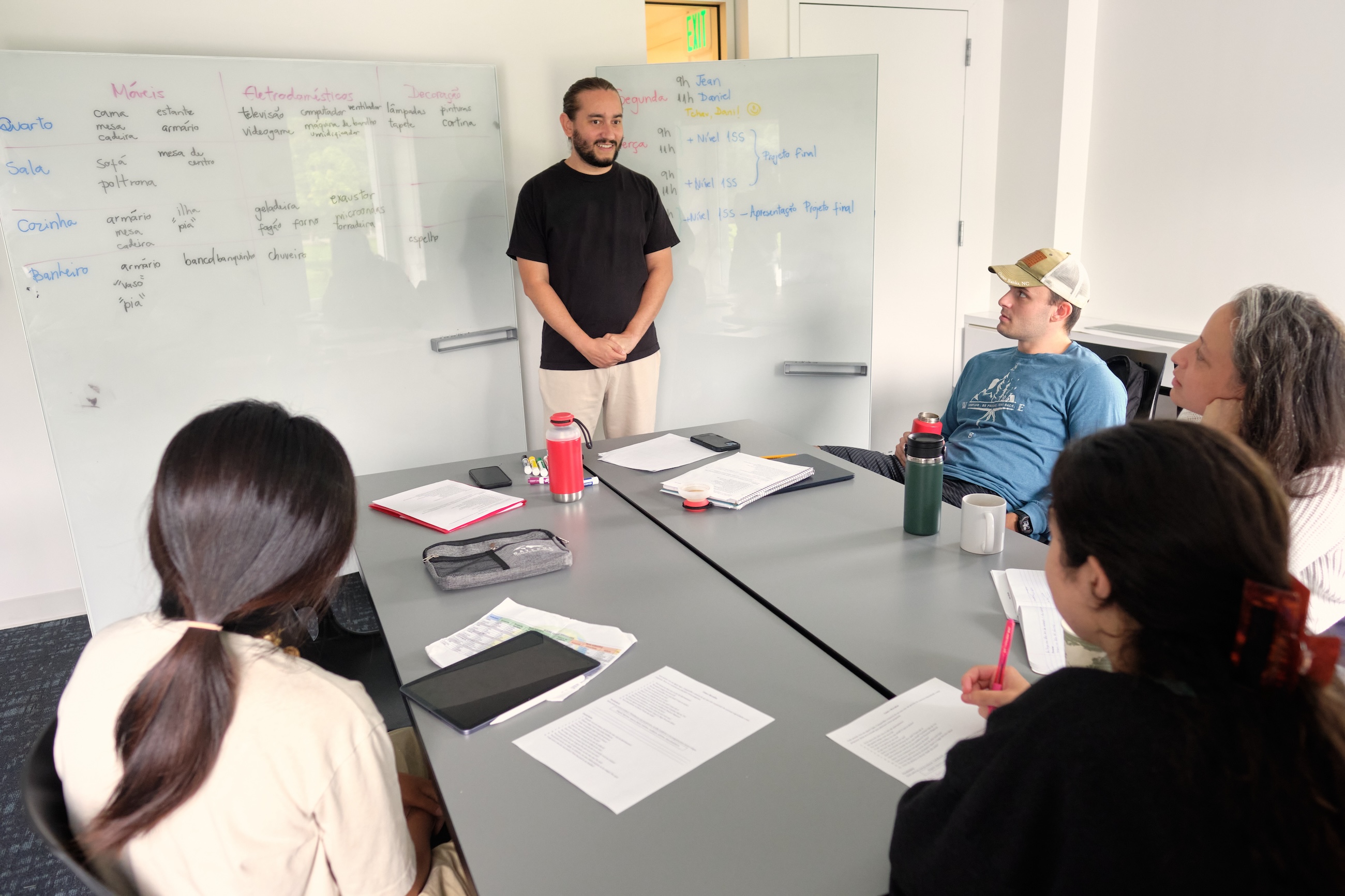 A Portuguese teacher smiles at the whiteboard. 