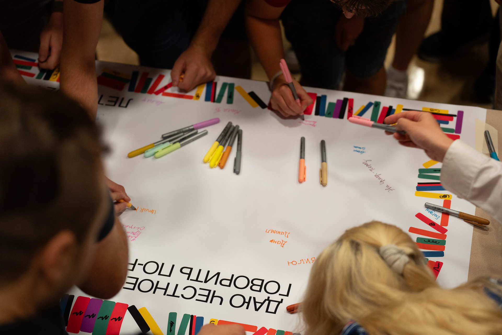 A colorful sign with Russian writing and colorful pens. 