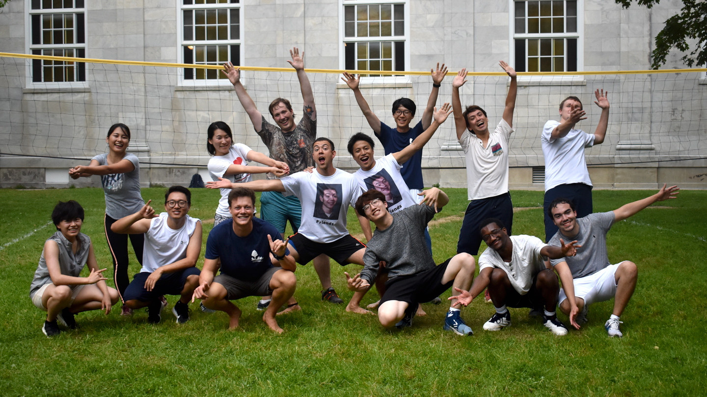 Students smile in front of a volleyball net on the Middlebury College campus. 