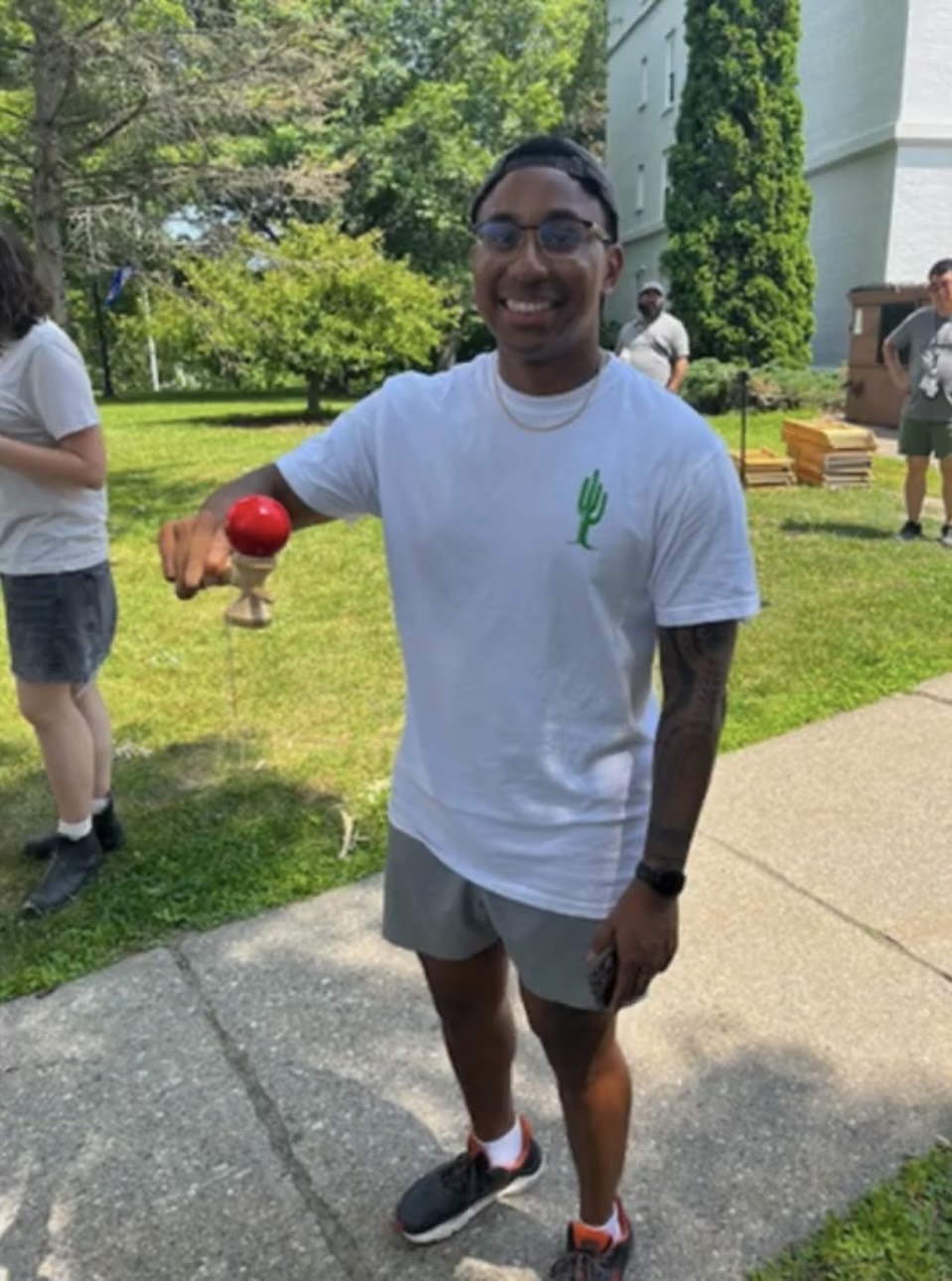 A man holds a ball on a wooden object with a concave top. 