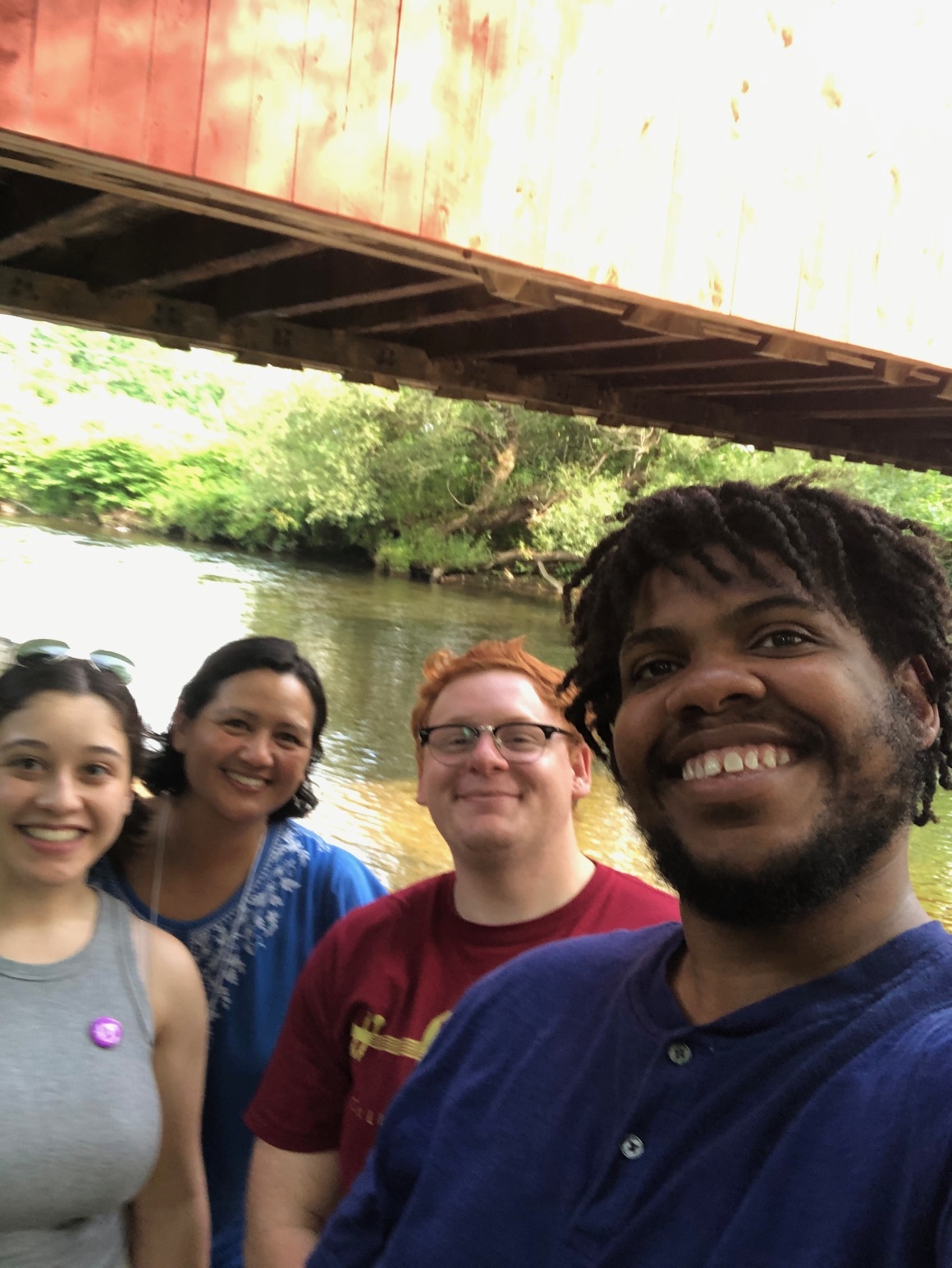 A man and his friends smile in front of a river. 