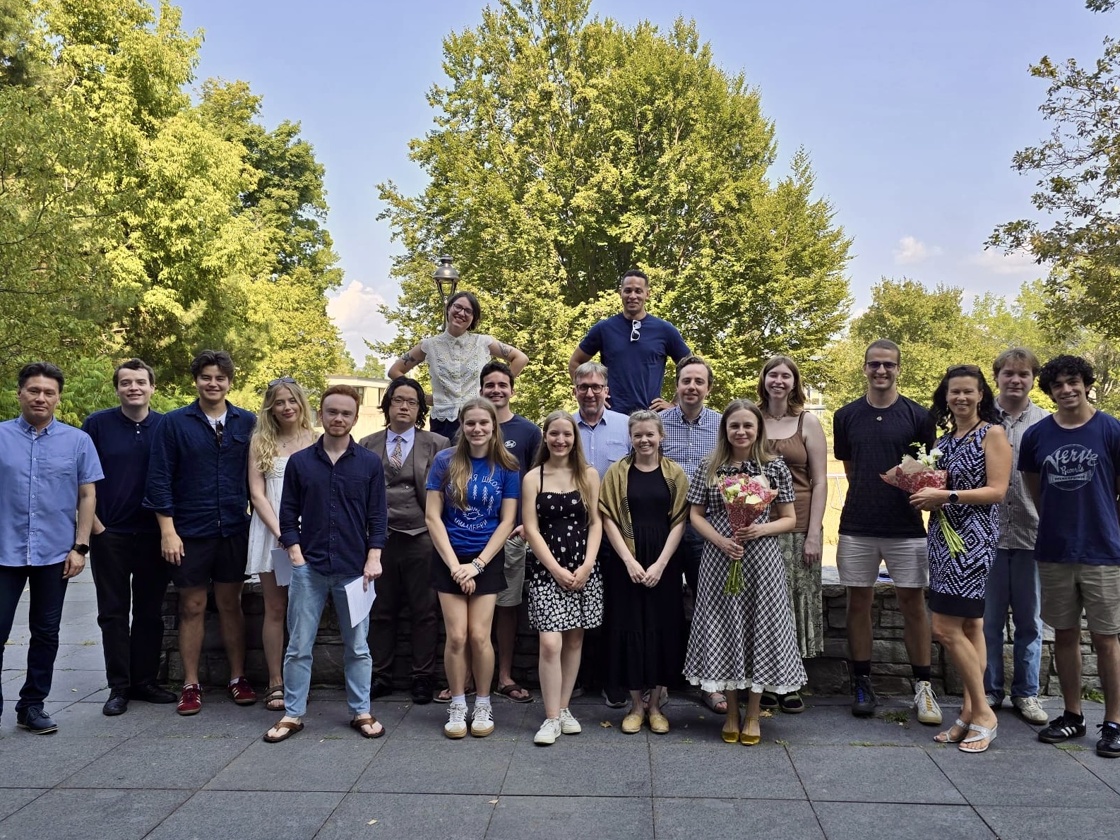 a group of students stands outside in a group, smiling