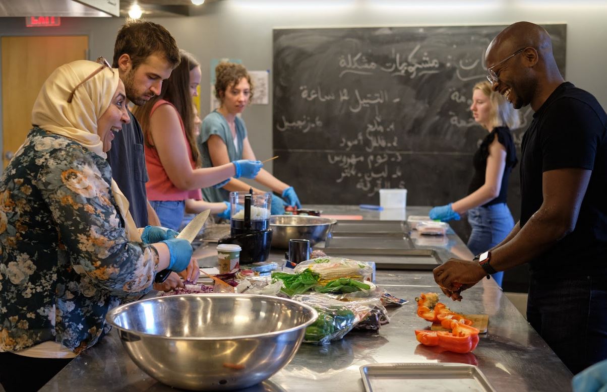 A group of people cooks together at a long table. 