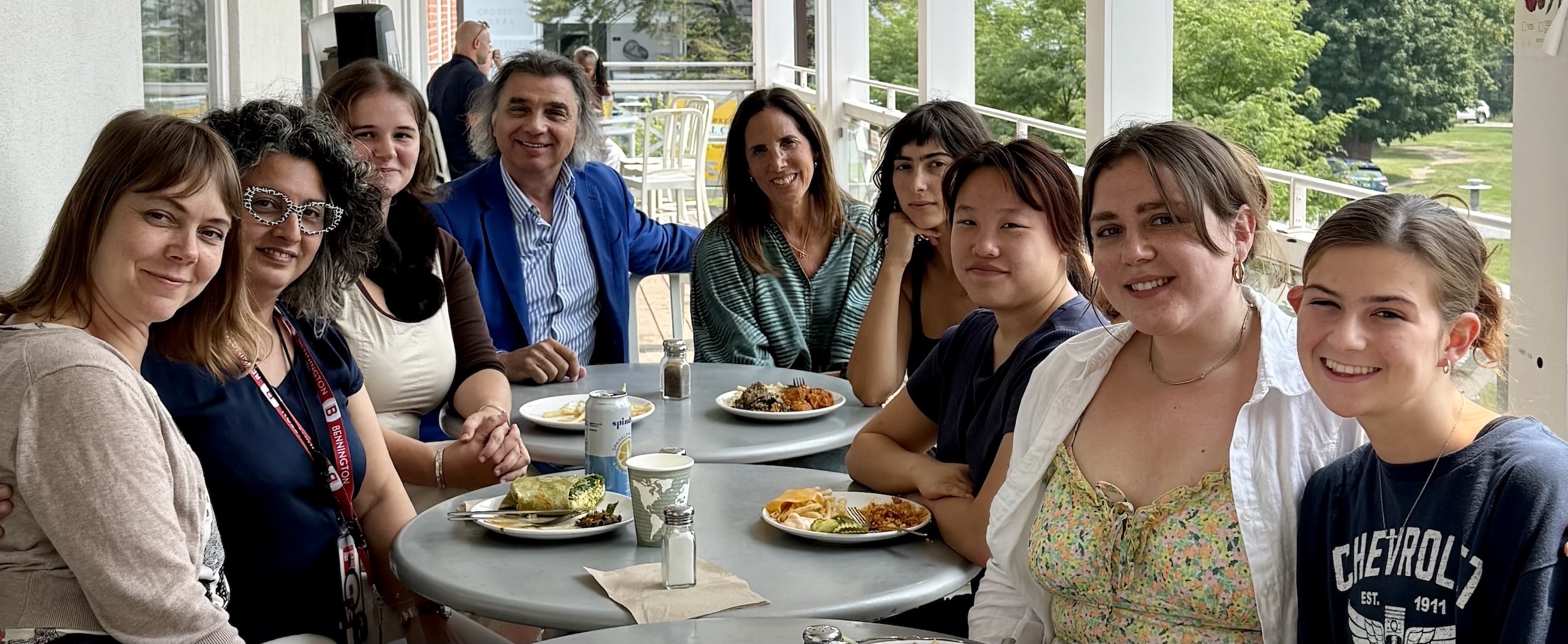 A group of Italian School students eat outside on a deck. 