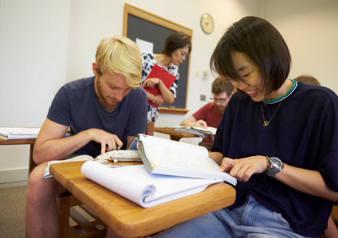 Two students study with a teacher.