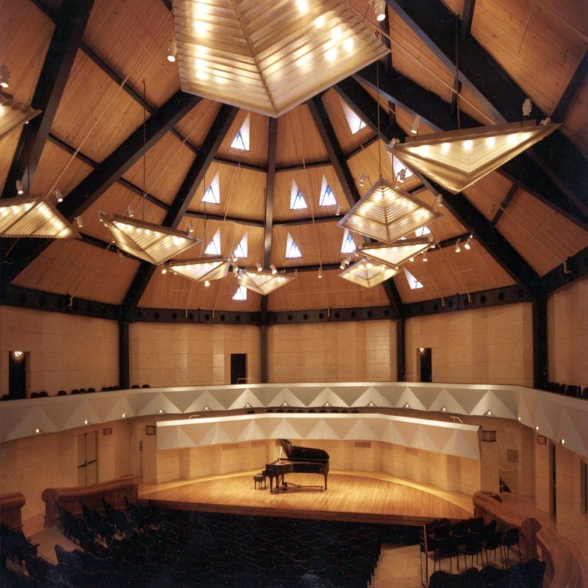 A concert hall with a grand piano on the stage. 