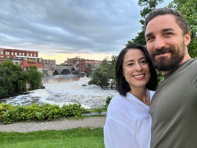 A couple smiles in front of the river in the town of Middlebury, Vermont